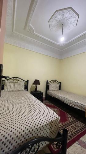 een slaapkamer met 2 bedden en een plafond bij Meuble BenTaleb Younes in Khenifra