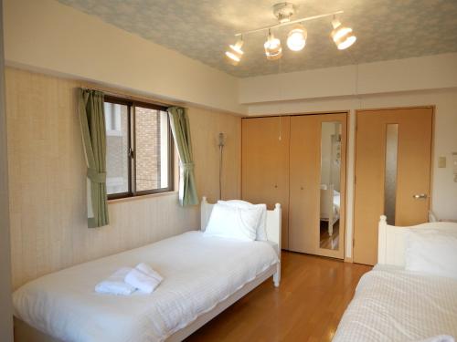 a bedroom with two beds and a window at ピオーレ大手門501 in Susakiuramachi