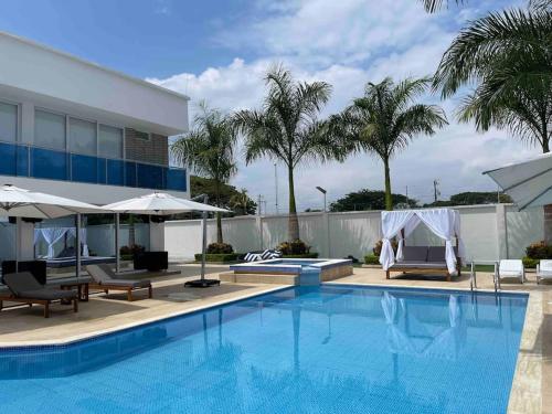 a pool with chairs and umbrellas next to a building at Chalét de Lujo en Rozo! in Rozo