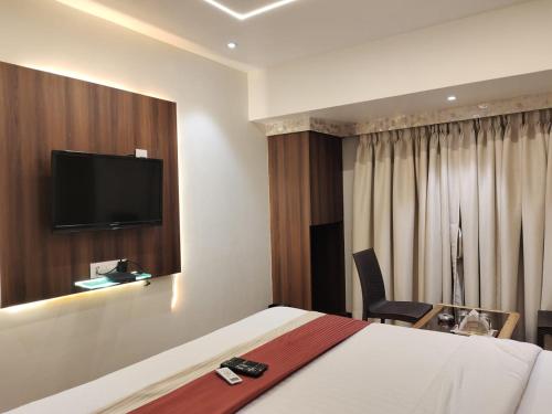 Una habitación de hotel con una cama y un televisor en la pared. en Hotel Shelter Palace, en Navi Mumbai