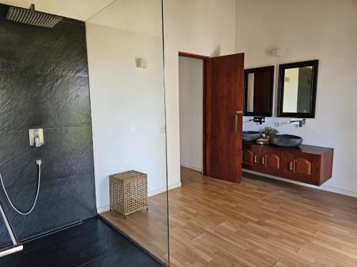 y baño con ducha con pared de cristal. en Vandalous Bay, en Pasikuda