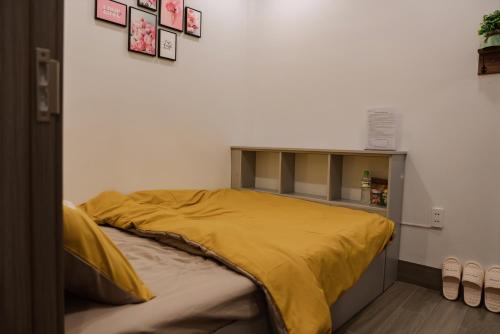 a bed with a yellow comforter in a room at Halidao Homestay in Hai Phong