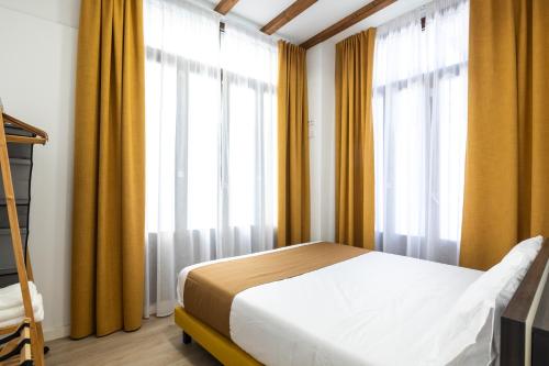 a bedroom with yellow curtains and a bed in front of a window at Moontels Plaza de Vannes in Valencia
