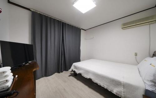 a hotel room with a bed and a flat screen tv at Greenbeach motel 그린비치 in Geoje