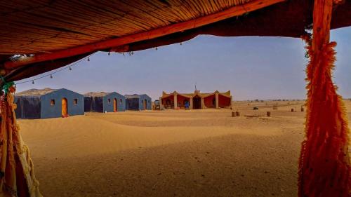 a group of huts in the middle of a desert at Camp Mbark authentic in Mhamid