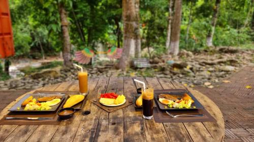 a wooden table with two plates of food and drinks at YesHue Eco in Hue