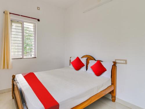 a bedroom with a bed with red and white pillows at OYO Flagship K V R Residency in Yelagiri