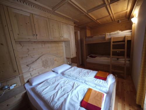 アラッバにあるAppartamento Brenteganiの小さな客室で、ベッド1台、二段ベッドが備わります。
