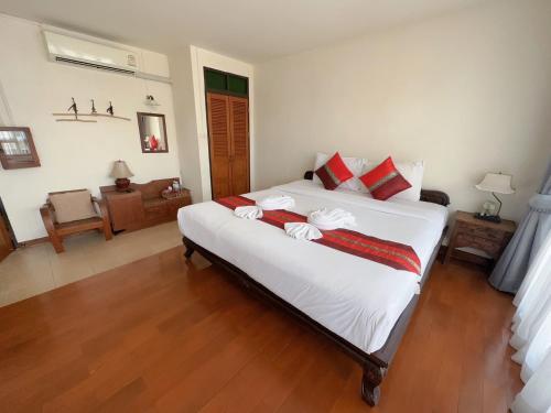 チェンマイにあるラスティック ゲスト ハウスのベッドルーム(赤い枕の大きな白いベッド付)