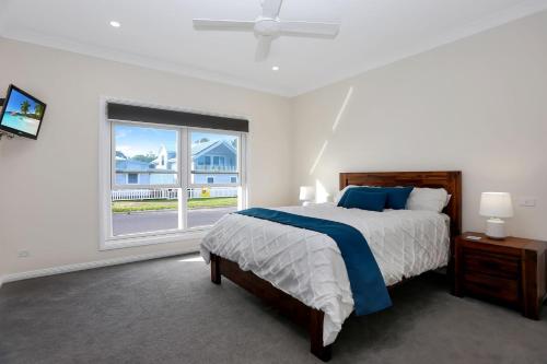 een witte slaapkamer met een bed en een raam bij Wataview Marine Drive in Tea Gardens
