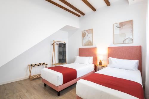 two beds in a room with white walls and wood floors at Moontels Plaza de Vannes in Valencia