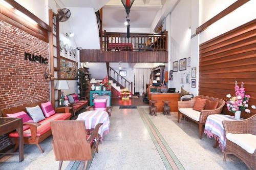 a living room with couches and chairs and a staircase at Rustic Guest House in Chiang Mai