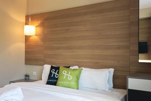 a bedroom with a wooden headboard and a bed at Homesuite' Home at Aeropod SOVO in Kota Kinabalu
