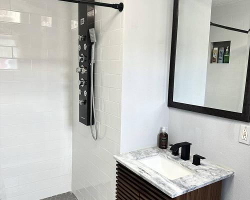 a bathroom with a sink and a mirror and a shower at Neptune's Cottage in Galveston