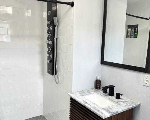 un bagno con lavandino, specchio e doccia di Neptune's Cottage a Galveston