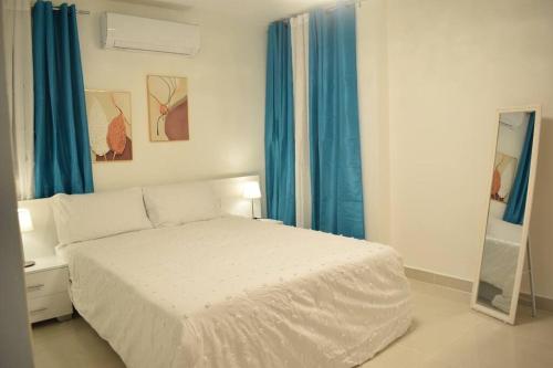 Schlafzimmer mit einem weißen Bett und blauen Vorhängen in der Unterkunft Apartamento en Santo Domingo zona universitaria in Santo Domingo