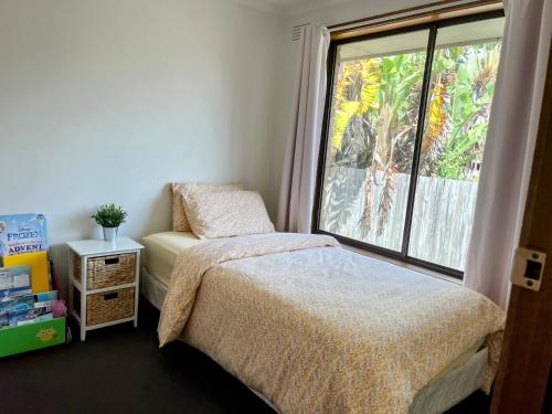 Un dormitorio con una cama y una ventana grande. en Stay next to train station! Melbourne CBD 12 km!, en Melbourne