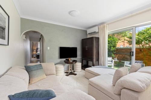 a living room with white couches and a flat screen tv at Northern Beaches Garden Hideaway in Sydney