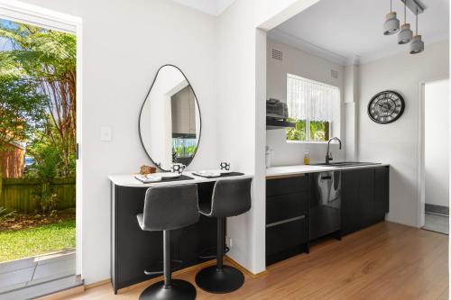 a bathroom with a vanity with a mirror and two chairs at Northern Beaches Garden Hideaway in Sydney