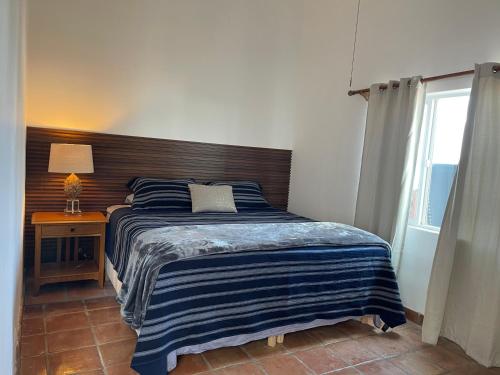 1 dormitorio con 1 cama con cabecero de madera y ventana en Baja Azul, en Ensenada