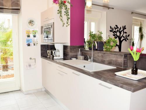 cocina con fregadero y pared púrpura en Séjour détente en Touraine : maison de charme avec spa, sauna, fitness, jardin clos et équipements pour bébé - FR-1-381-473, en Benais