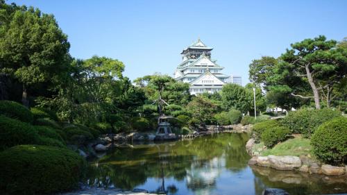 a pond in a garden with a building in the background at Toyoko Inn Osaka Kyobashi Sakuranomiya in Osaka