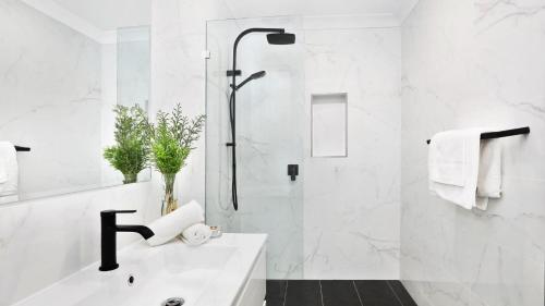 a white bathroom with a shower and a sink at Ravello in Callala Bay
