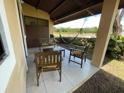 a porch with two chairs and a table and a hammock at Acogedora casa en Alto Boquete, Las Trancas 1 in Boquete