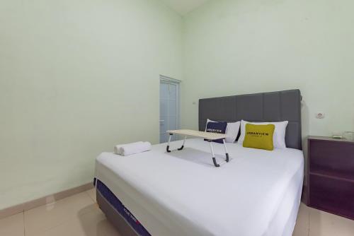 uma grande cama branca com uma mesa em cima em Urbanview Hotel Nakasya Burangrang em Bandung