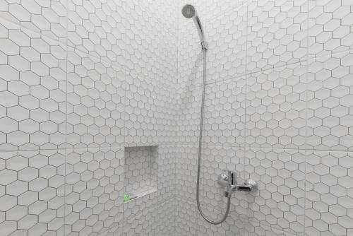 uma casa de banho com um chuveiro com paredes em azulejos brancos em Urbanview Hotel Nakasya Burangrang em Bandung