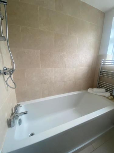 a white bath tub in a bathroom with a shower at Maple Lodge in South Norwood