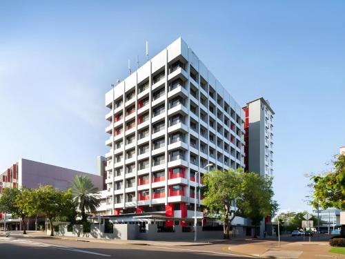 un edificio alto blanco y rojo en una calle de la ciudad en The Smith Hotel Darwin, en Darwin
