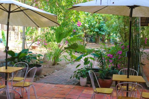 a patio with tables and chairs and an umbrella at Casa Kep Eco Bed & Breakfast in Kep