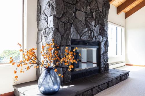 a blue vase with flowers in front of a fireplace at Unmatched Ocean Beach and Mountain Views Family-Friendly Retreat in Moss Beach