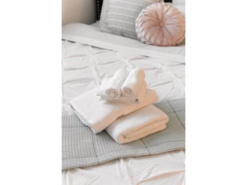einen Stapel Handtücher auf dem Bett in der Unterkunft The Flamingo 102 l Pool I 65 Smart TV I Sleeps 5 in Austin
