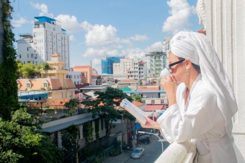 una mujer hablando por celular mientras mira una ciudad en Grand Elevation Hotel, en Phnom Penh