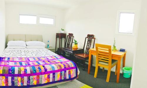 LilyのHome Elegant Retreat near Riccarton Mall في كرايستشيرش: غرفة نوم بسرير ومكتب وطاولة