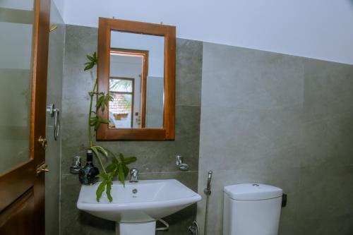 a bathroom with a sink and a mirror and a toilet at T20 Mirissa in Mirissa