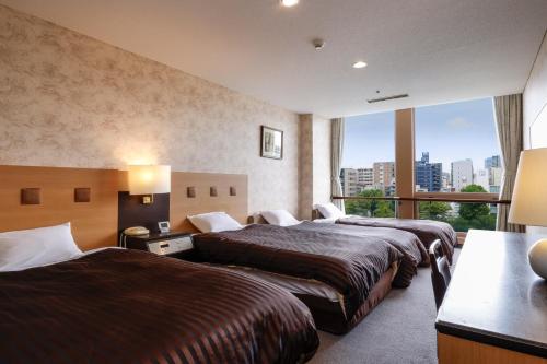 Habitación de hotel con 2 camas y ventana grande. en Hotel Osaka Castle, en Osaka