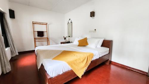 a bedroom with a bed with a yellow blanket on it at Mango Tree Villa in Unawatuna