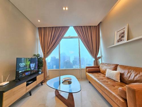 a living room with a leather couch and a large window at Sky Suites KLCC Kuala Lumpur in Kuala Lumpur