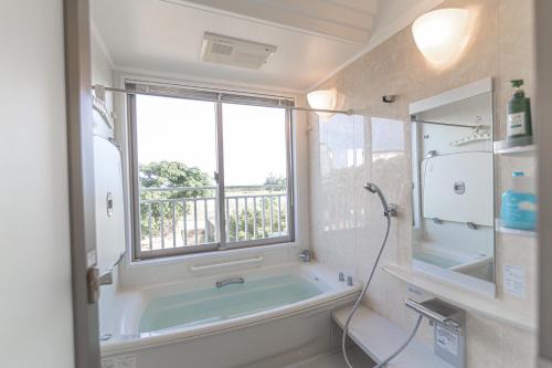 La salle de bains est pourvue d'une baignoire et d'une fenêtre. dans l'établissement Estrella Maezato - Vacation STAY 69423v, à Ōhama