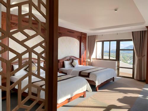 a bedroom with two beds and a large window at Rex hotel An Nhon 