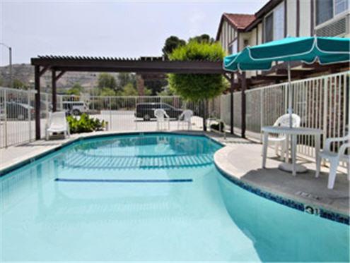 a large swimming pool with chairs and an umbrella at Super 8 by Wyndham Santa Clarita/Valencia in Santa Clarita