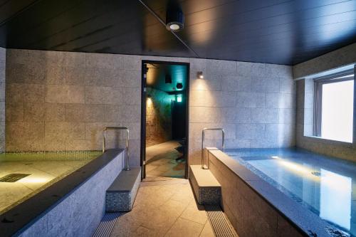 a bathroom with a large swimming pool with a window at 3s HOTEL ATSUGI in Atsugi