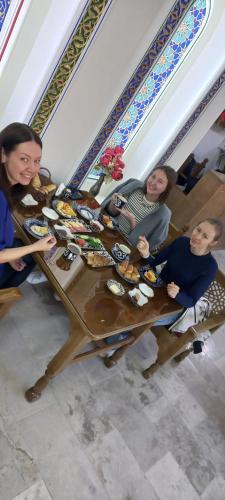 Hotel Zarhal في بوكسورو: ثلاث نساء جالسات على طاولة عليها طعام