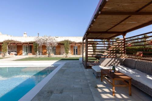 a patio with a table and a swimming pool at Masseria Misocampo - Happy Rentals in Calimera
