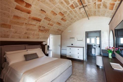 a bedroom with a large bed and a stone wall at Masseria Misocampo - Happy Rentals in Calimera