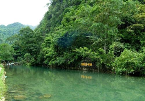 une rivière avec un panneau au milieu d'une forêt dans l'établissement Mai Anh Homestay - Pac Bo Village, 