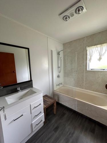 a bathroom with a tub and a sink and a mirror at Town Centre Retreat in Taupo
